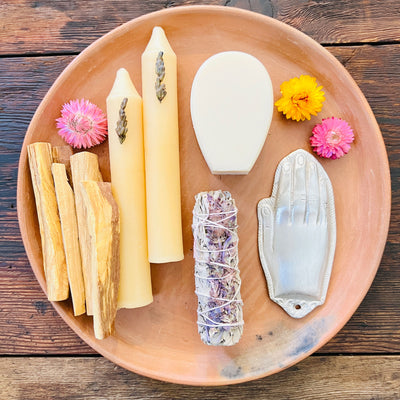 Collection photo for our "Shop By Color: Self Care" collection. Image is top view photo of a clay plate containing palo santo sticks, candles, soap, sage bundles, and flowers