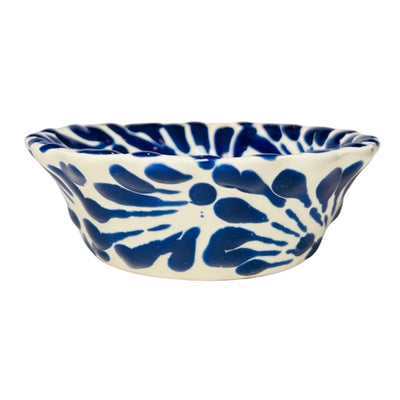side view of a blue and white Puebla design ceramic bowl with a scalloped edge