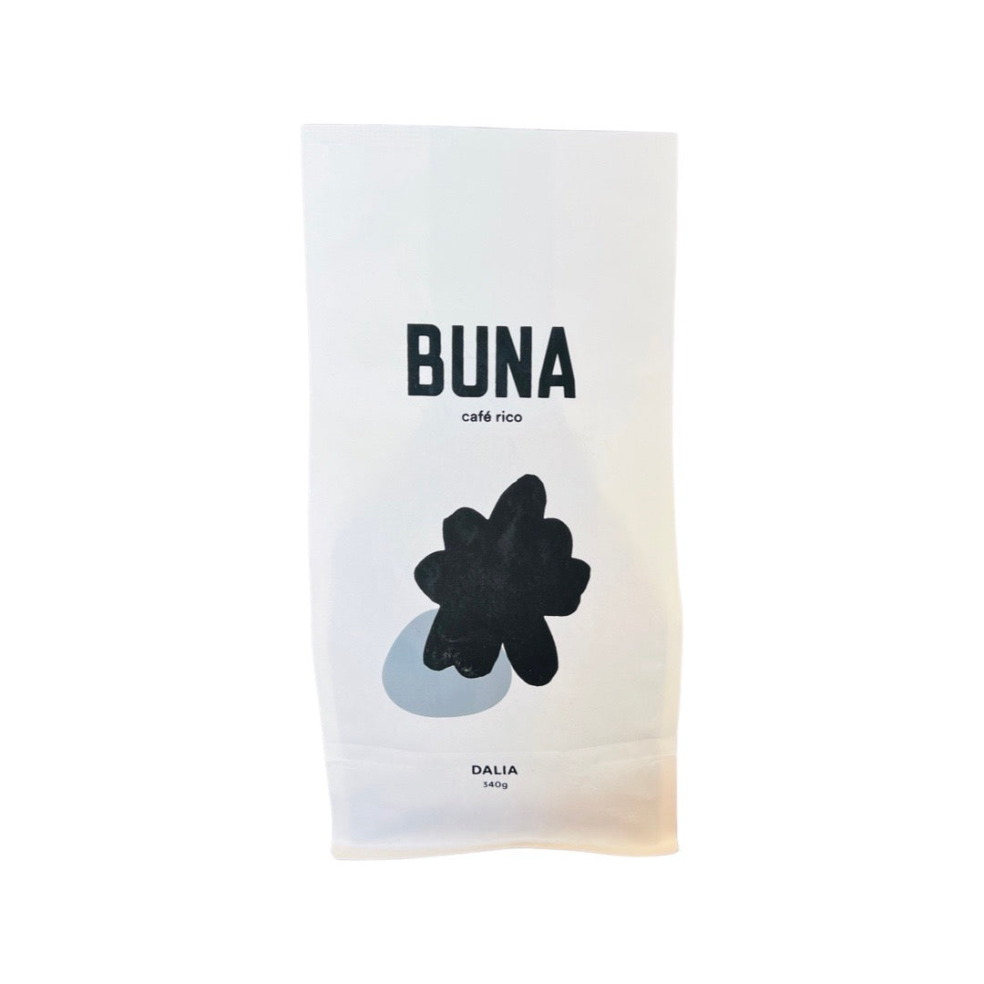 A single white 340 gram bag of Buna Coffee that features abstract art of a black splatterover a gray spot on the center of the bag.