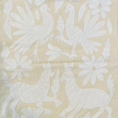 enhanced view of white floral and fauna scenery detail embroidered on off white table runner