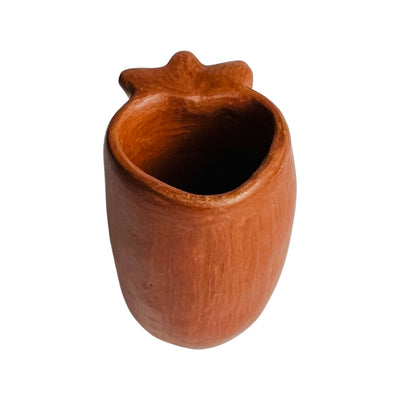Side view of a red clay shot glass with a heart design