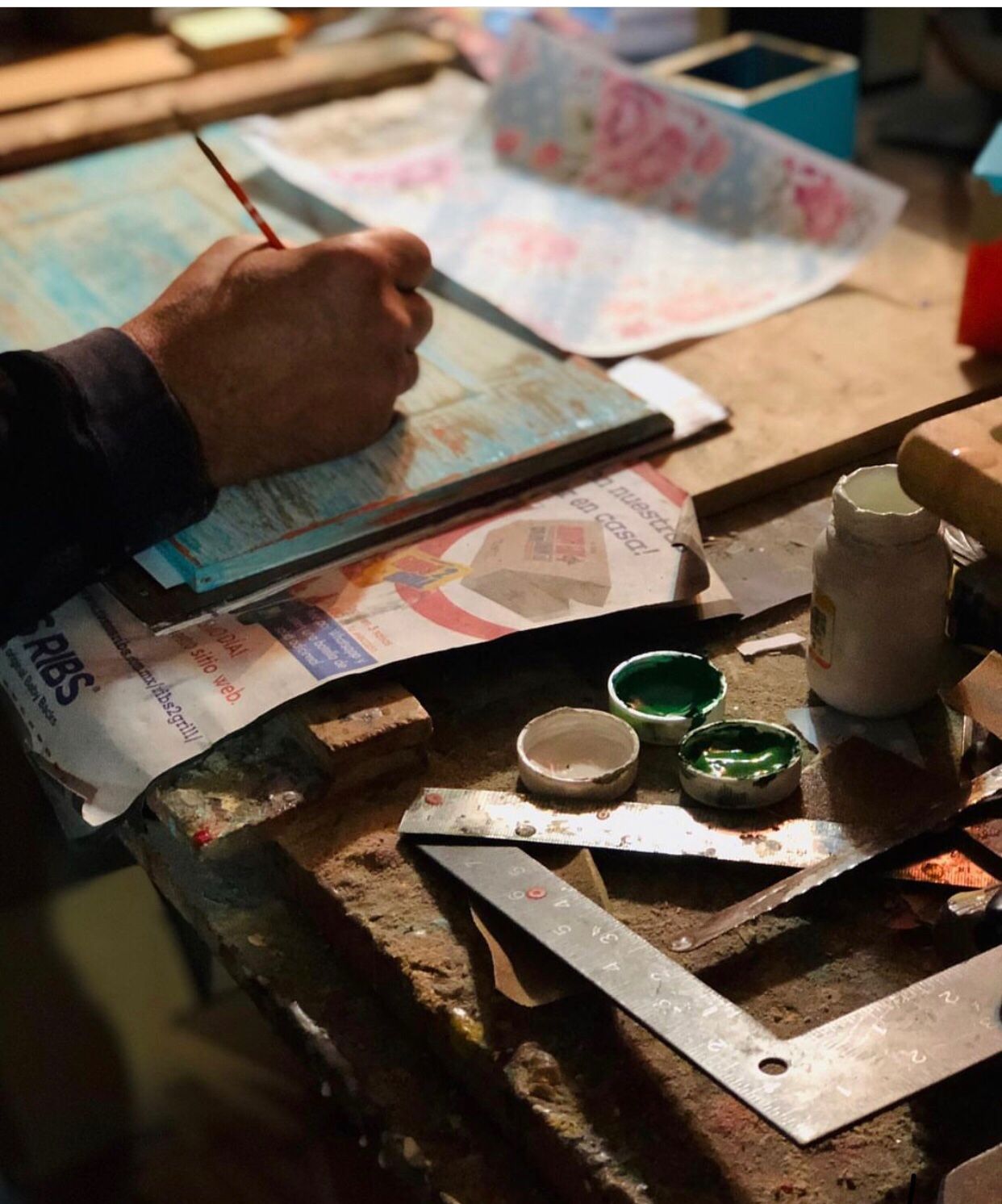 Hand of Mexican artisan Ignacio Haro painting on a canvas