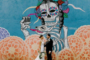 Bride & groom posing in front of mural in mexico