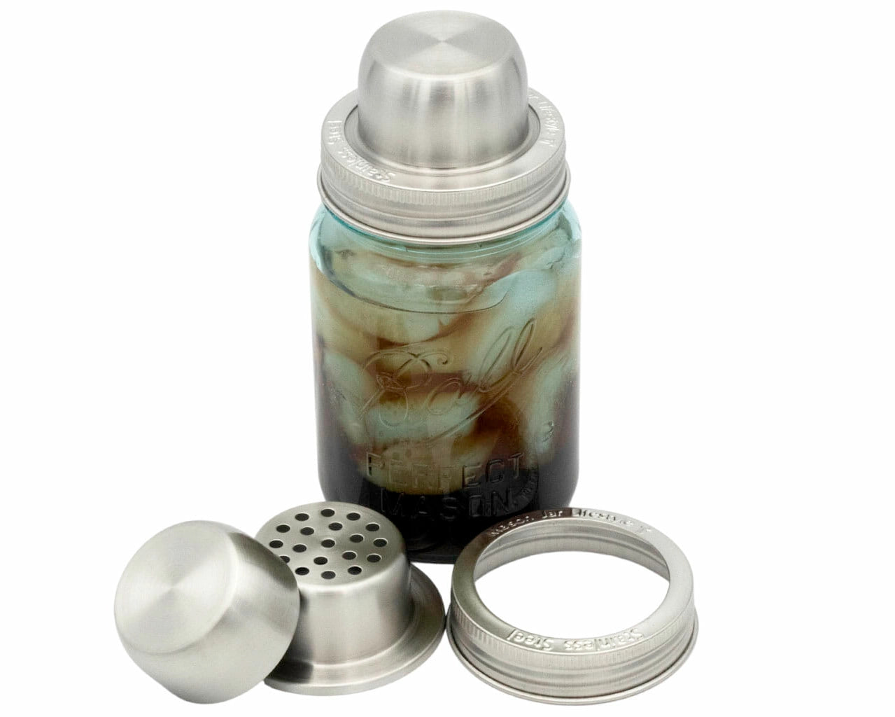 A mason jar filled with ice and liquid, fitted with a stainless steel cocktail shaker lid, with the strainer, cap, and screw band shown separately in front.