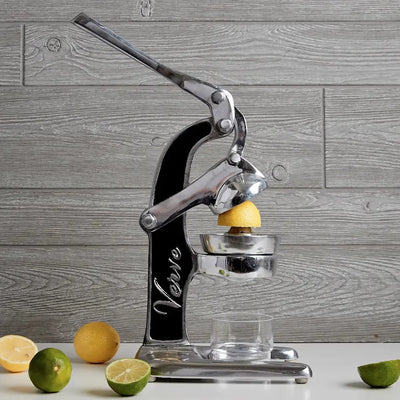 Aluminum juicer with slices of lemons and lime and a glass.