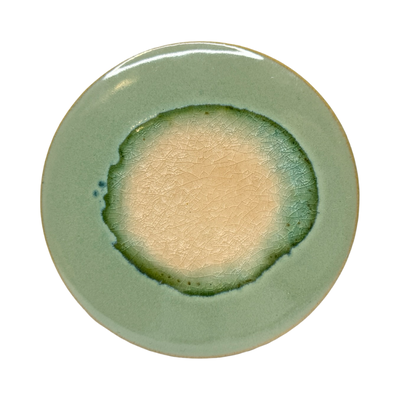 dark green round stoneware trivet with two-tone reactive glaze, showing slight variations in finish.