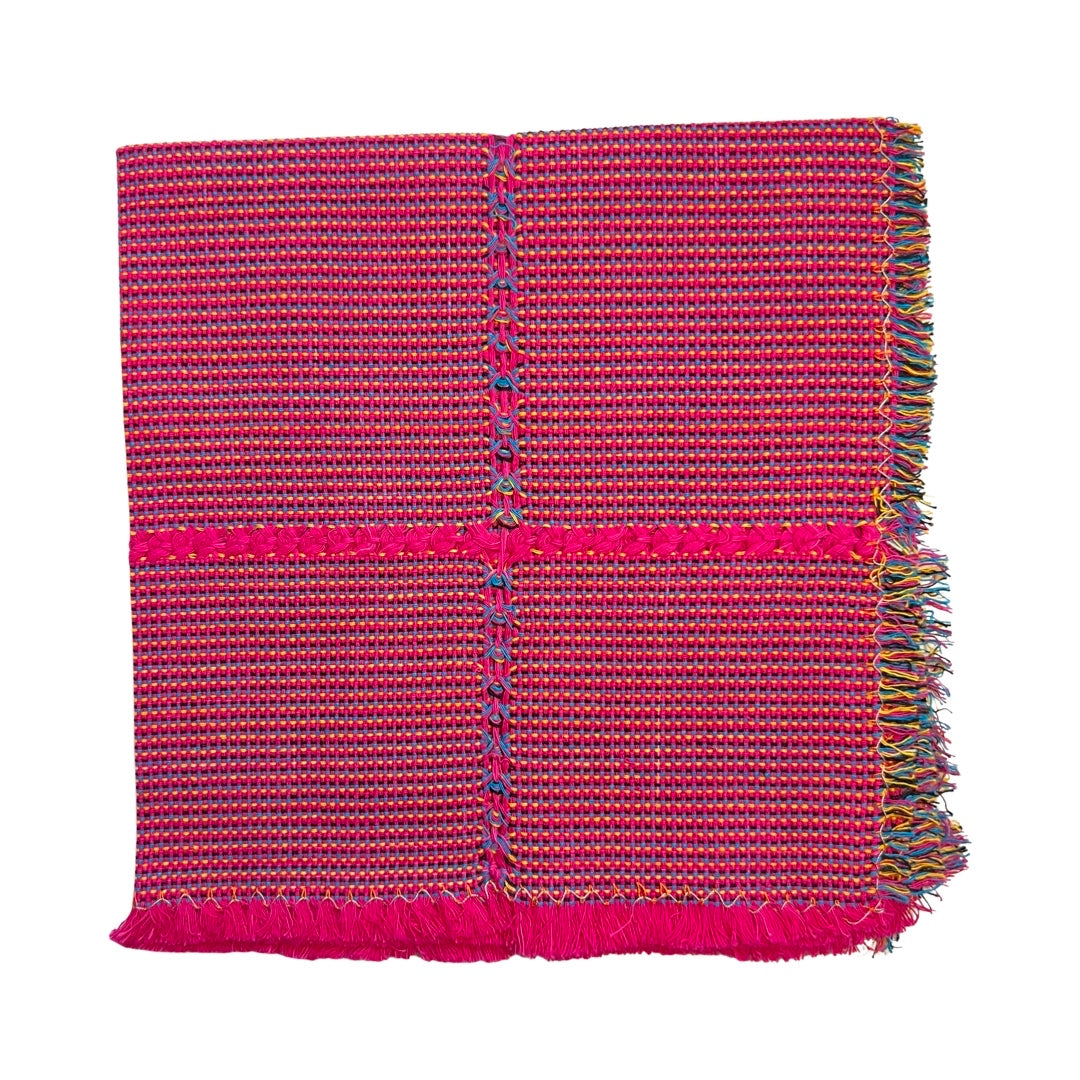 pink striped handwoven napkin with multi-colored fringe folded in quarters