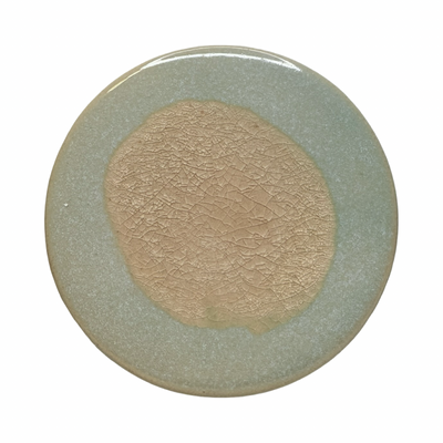 light grey round stoneware trivet with two-tone reactive glaze, showing slight variations in finish.