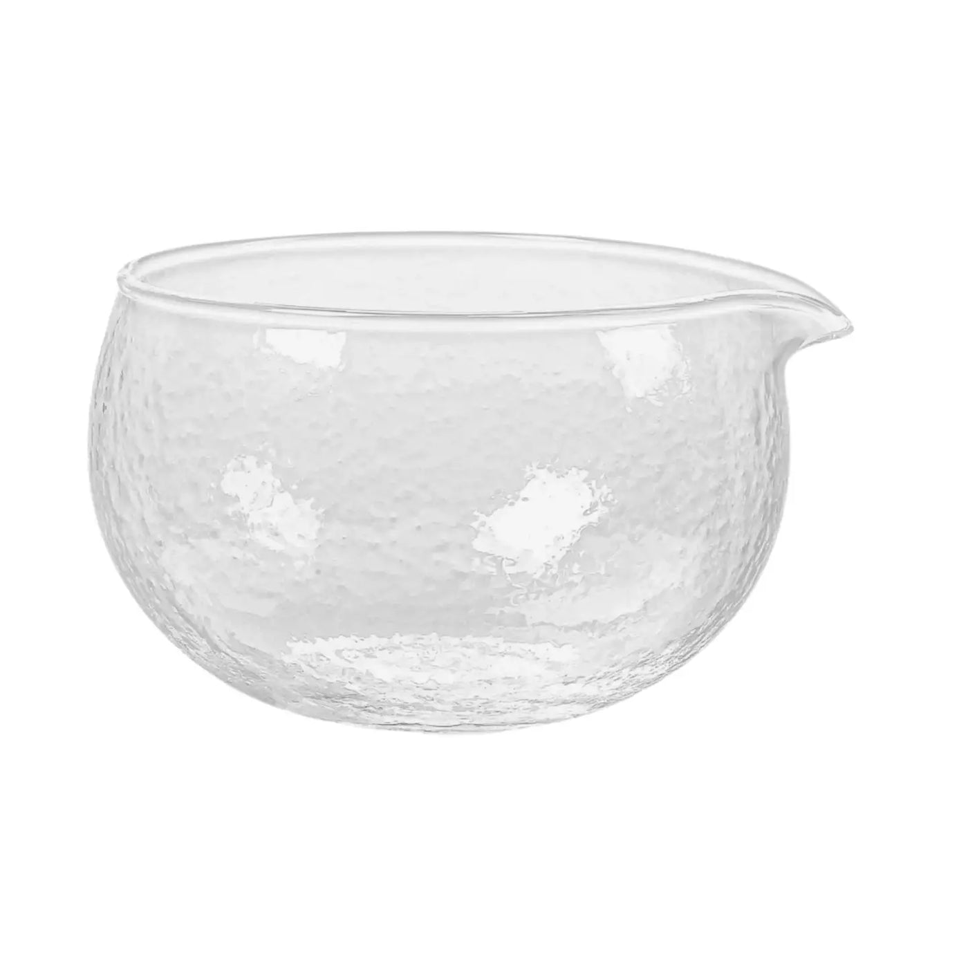 Clear, round glass matcha bowl with a small pouring spout and lightly hammered texture.