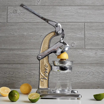 Aluminum juicer with slices of lemons and lime and a glass.