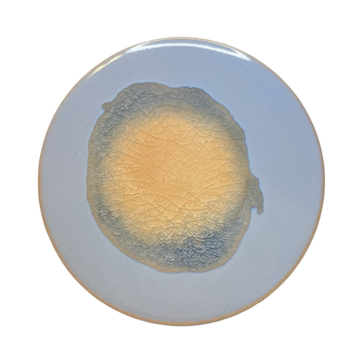 light purple/blue round stoneware trivet with two-tone reactive glaze, showing slight variations in finish.