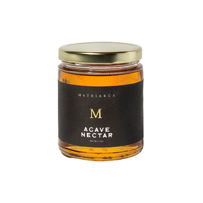 11 oz Glass jar filled with amber agave syrup, labeled “Agave Nectar” by Matriarca, with a black and gold label and gold lid.