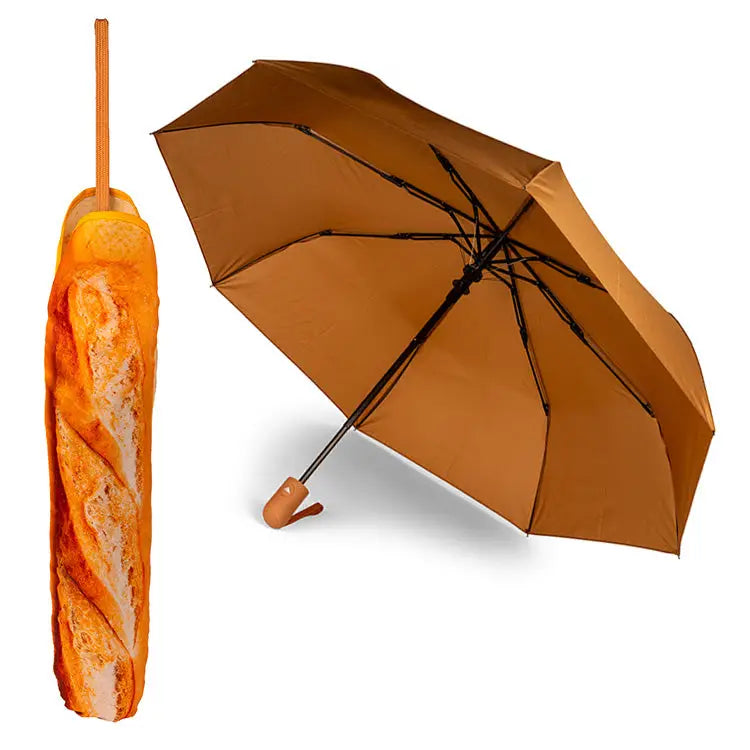 A copper colored umbrella sits open next to an image of the umbrella closed inside a whimsical umbrella cover that looks like a freshly baked french baguette.