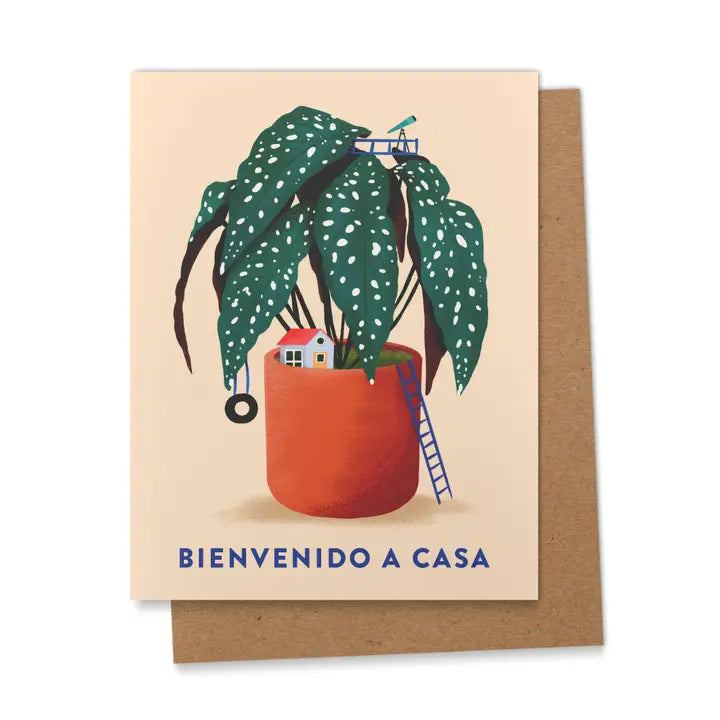 Greeting card with a potted green plant featuring white spots, a small house, ladder, tire swing, and the words “Bienvenido A Casa” in blue letters with a kraft envelope.