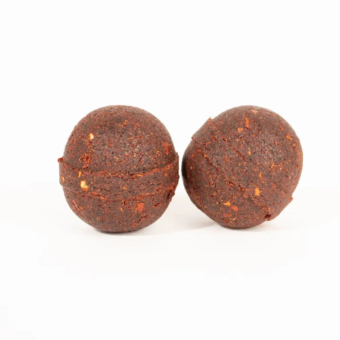 Two dark reddish-brown Birria Bomb seasoning balls with visible spice flecks, placed side by side.
