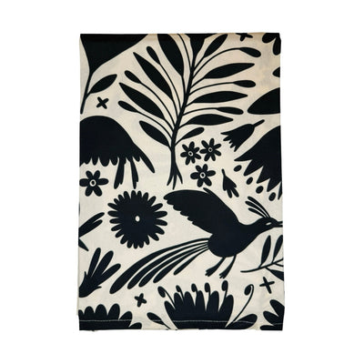 Kitchen towel with black Otomi-inspired designs of birds, flowers, and leaves on a cream background.