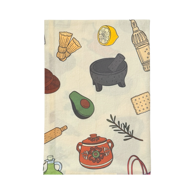 Cream kitchen towel covered in illustrated Mexican-kitchen motifs including a black molcajete with pestle, wooden molinillo, avocado half, lemon slice, rosemary sprig, terracotta pot, rolling pin, cracker, and oil bottle folded in quarters.
