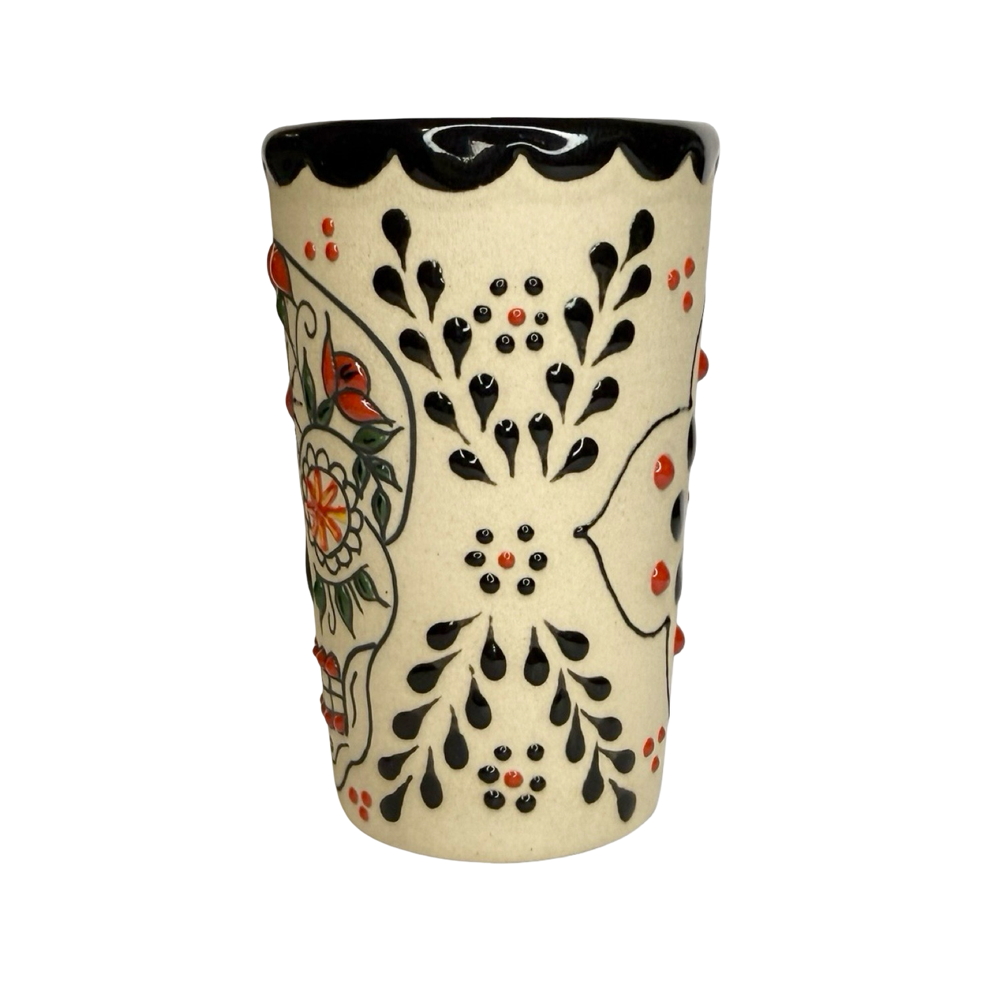 cream ceramic shot glass decorated with colorful sugar skull (Catrina) designs in red, black, and orange.