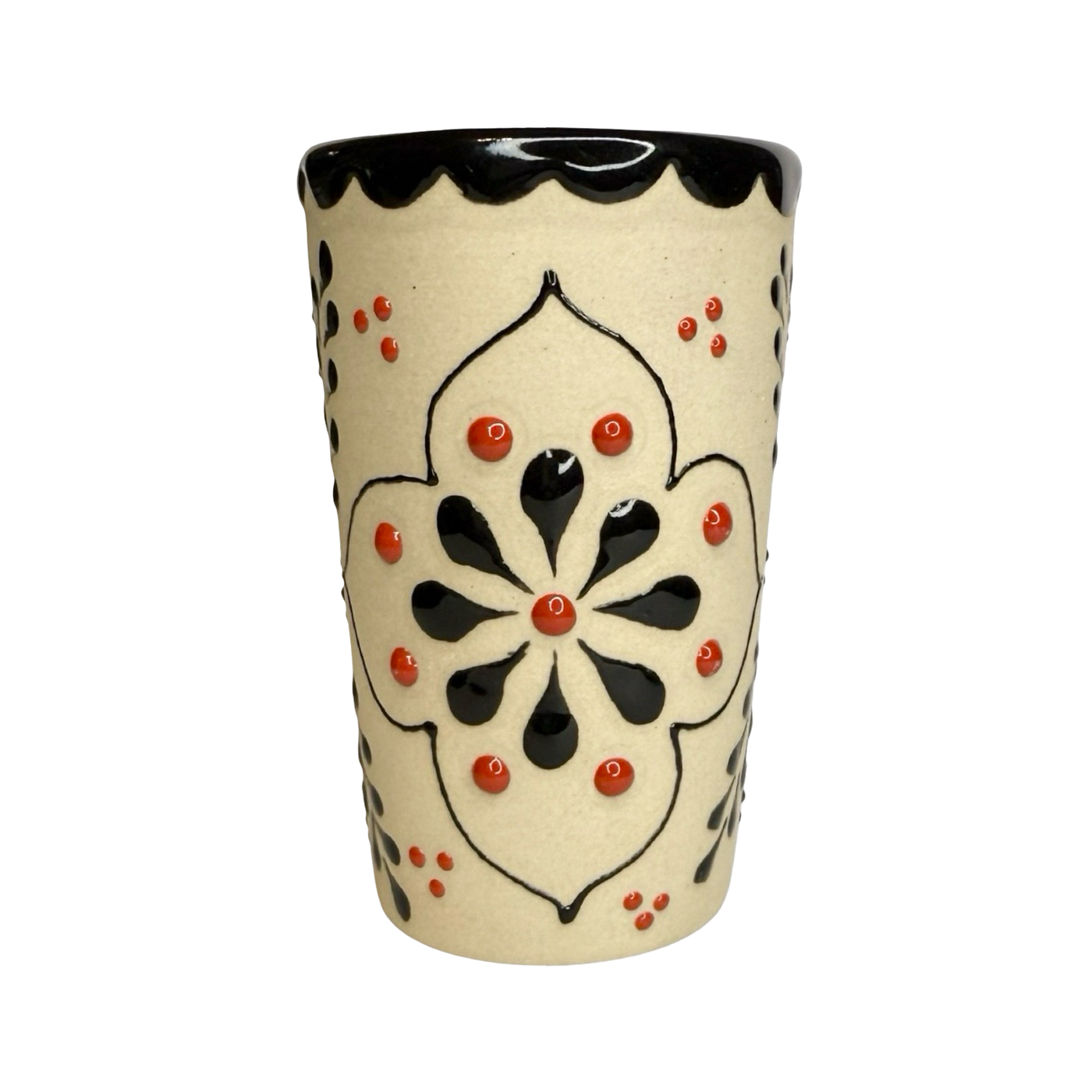 cream ceramic shot glass decorated with colorful floral designs in red, black, and orange.