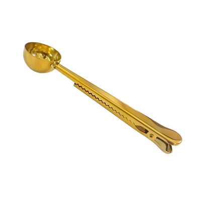 side view of a gold coffee or tea scoop with a built-in clip