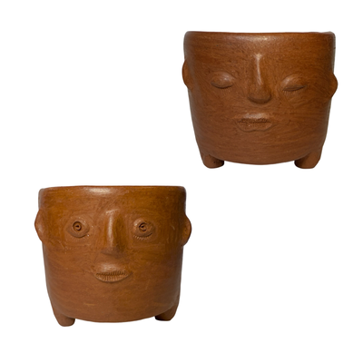 two barro rojo pots featuring two expressive faces—one wide-eyed and curious, the other calm and dreamy.
