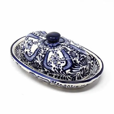 A hand-painted ceramic butter dish with a domed lid, decorated in intricate blue floral and leaf patterns on a white background, featuring a round blue knob on top.