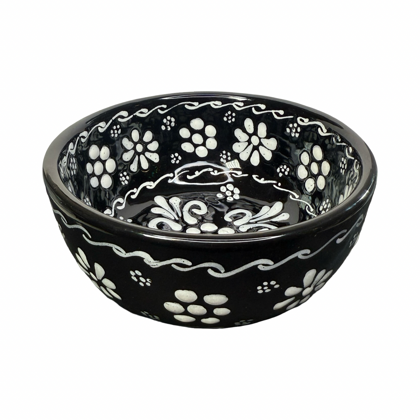 Side view of a black ceramic bowl hand-painted with white floral and scrollwork designs.