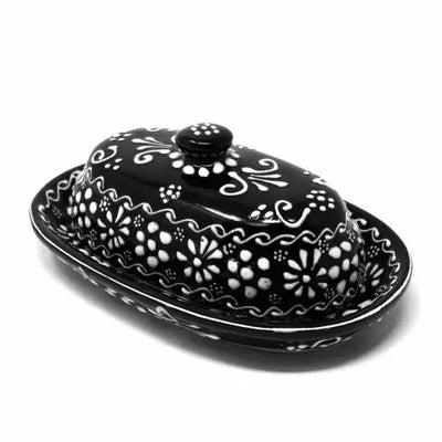 Black ceramic butter dish with white floral patterns on a white background