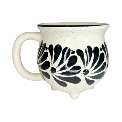 speckled cream ceramic perol mug with hand-painted black floral designs, rounded shape, and small feet at the base.
