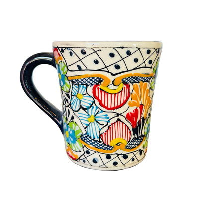 one ceramic mug that features the traditional Mexican talavera design with blues, yellows, reds and black.