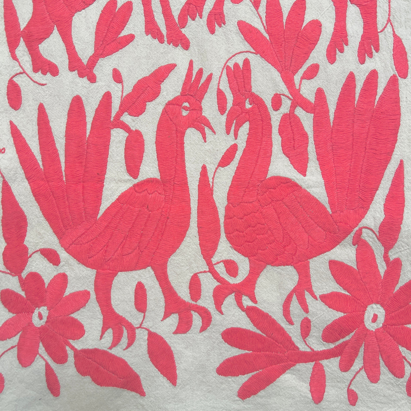 enhanced view of pink floral and fauna scenery detail embroidered on off white table runner