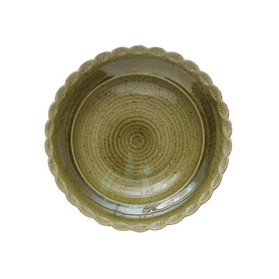 Top view of a green stoneware bowl showing a circular textured pattern and scalloped rim with subtle glaze variations.