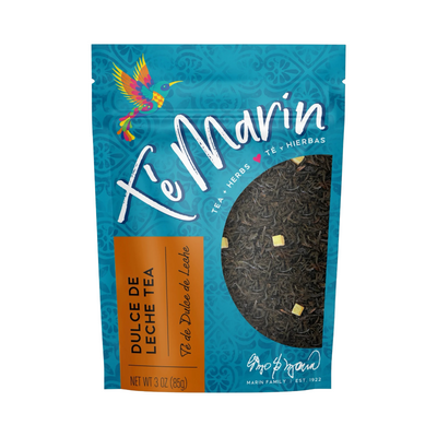 A teal resealable bag of Té Marín Dulce De Leche Tea with a clear window showing the loose herbal blend inside. The packaging features a colorful hummingbird and text in English and Spanish.
