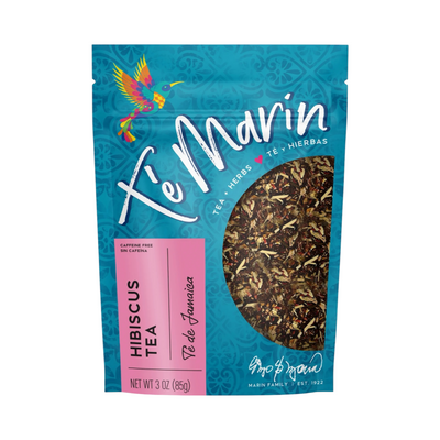 A teal resealable bag of Té Marín Hibiscus Tea with a clear window showing the loose herbal blend inside. The packaging features a colorful hummingbird and text in English and Spanish.