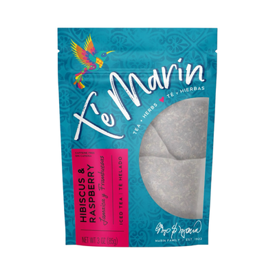 A teal resealable bag of Té Marín Hibiscus & Raspberry Tea with a clear window showing the loose herbal blend inside. The packaging features a colorful hummingbird and text in English and Spanish.