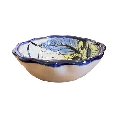 side view of a round dish with a blue scalloped edge with a bird and flower design.