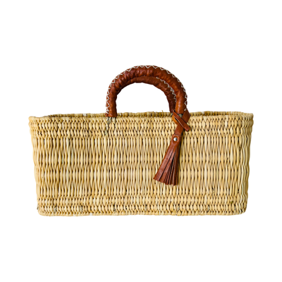 A rectangular woven reed market basket with sturdy leather-wrapped handles and tassel.