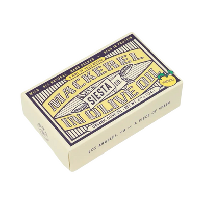 A cream-colored tin of Siesta Co. Mackerel in Olive Oil with Yuzu Koshō, featuring vintage-style typography in navy and gold with a small yellow lemon illustration in the corner.