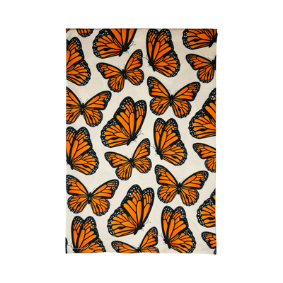 Kitchen towel with a repeating pattern of vibrant orange and black monarch butterflies on a cream background.