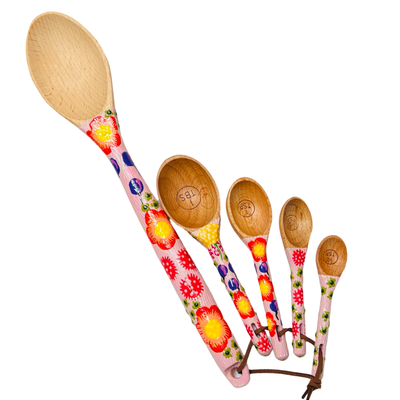 set of wooden measuring spoons and a baking spoon with handpainted handles with a pink floral design.