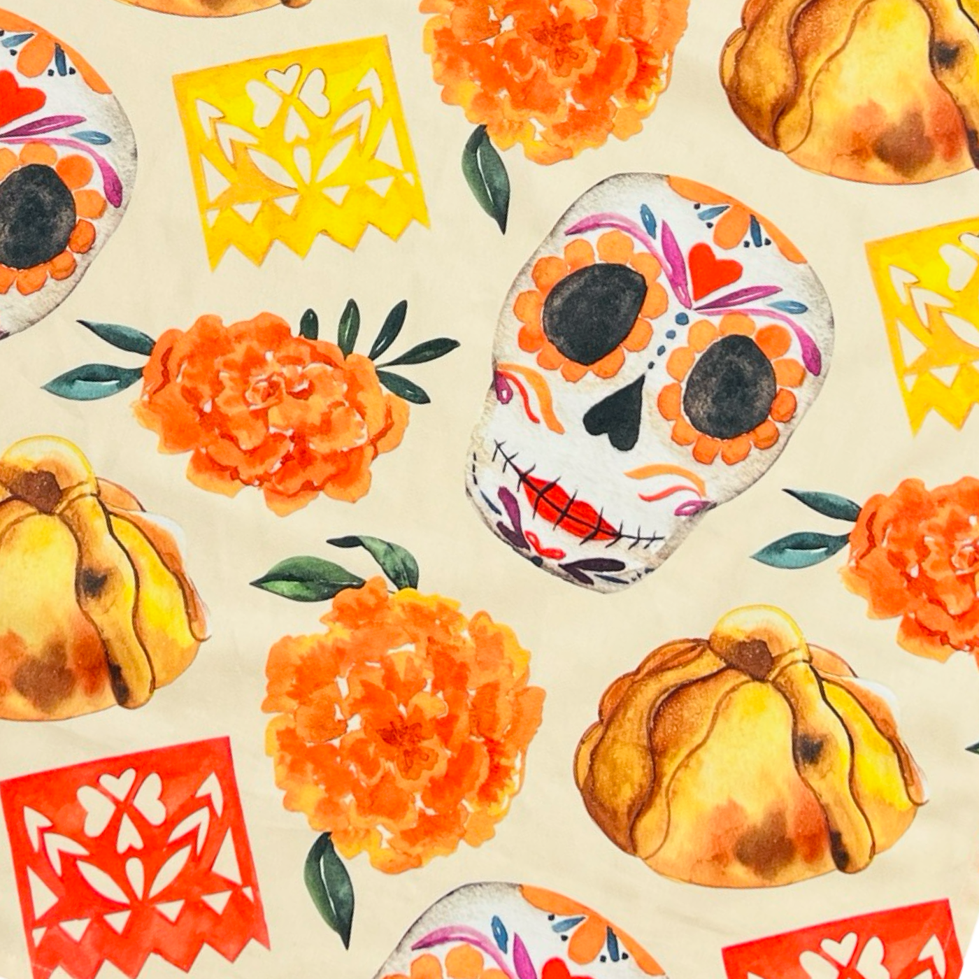 close up view of a beige apron with images of sugar skulls, pan de muerto, marigolds and papel picado banner featuring orange waist and neck ties.