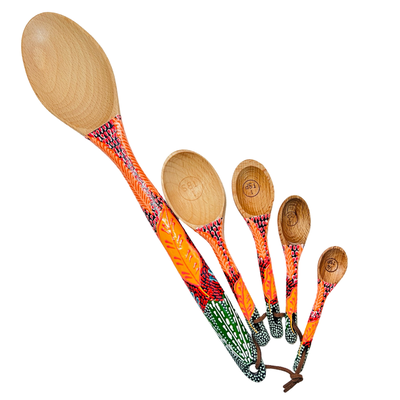 set of wooden measuring spoons and a baking spoon with handpainted handles with a orange leaf design.