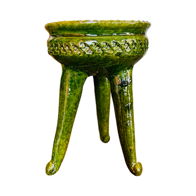 Side view of a three legged copalero, incense holder, with a green glaze.