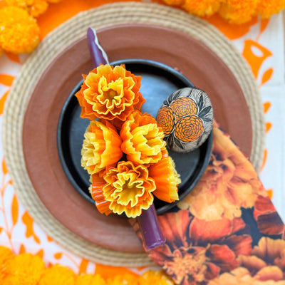 photo of purple stick candle decorated with multiple wax marigolds 