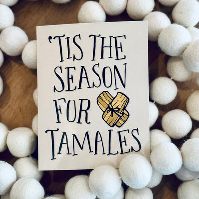 Front of greeting card with beige background & black text that reads "'Tis The Season For Tamales"