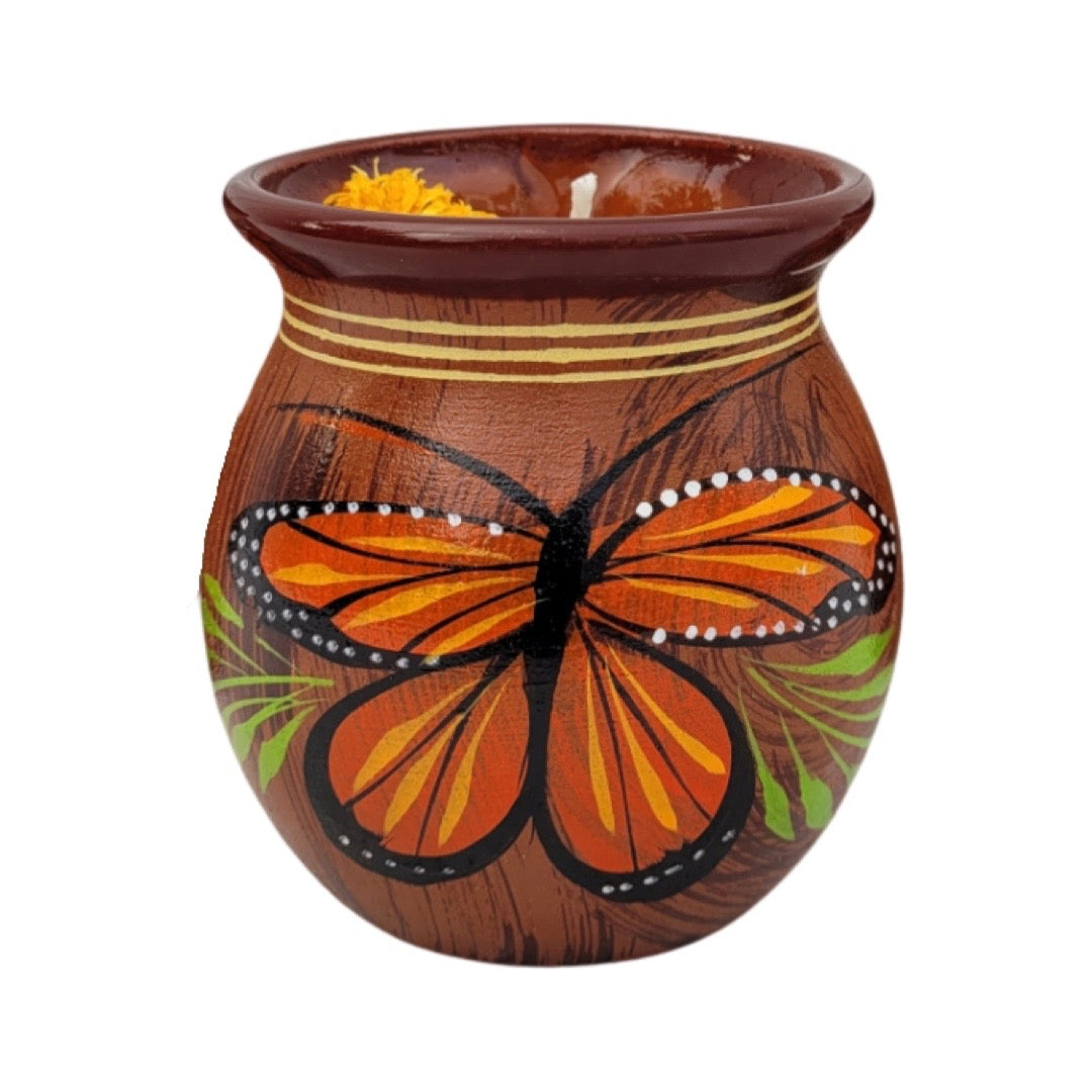 red barro mug with a hand painted monarch and features dried flowers and crystals on the candle wax.