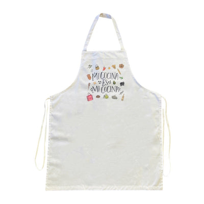 white apron with the phrase Mi Cocina es Mi Cocina in black lettering featurng various images of Mexican kitchen essentials such as tortilla press, pitcher, molcajete and pots.