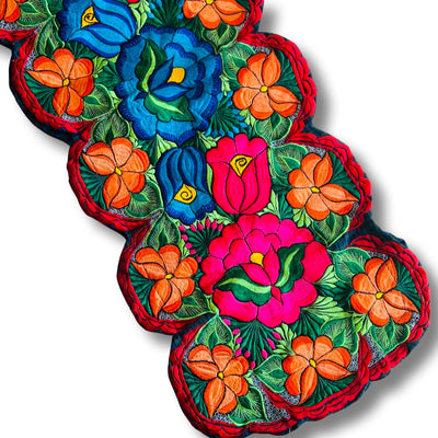 Diagonal picture of a table runner that features brightly colored embroidered flowers.