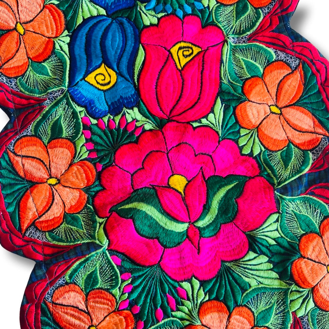 Closeup picture of a table runner that features brightly colored embroidered flowers.