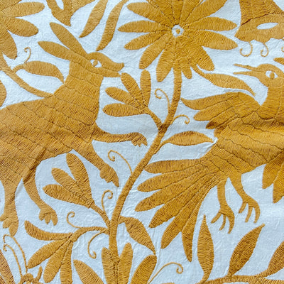 enhanced view of yellow floral and fauna scenery detail embroidered on off white table runner